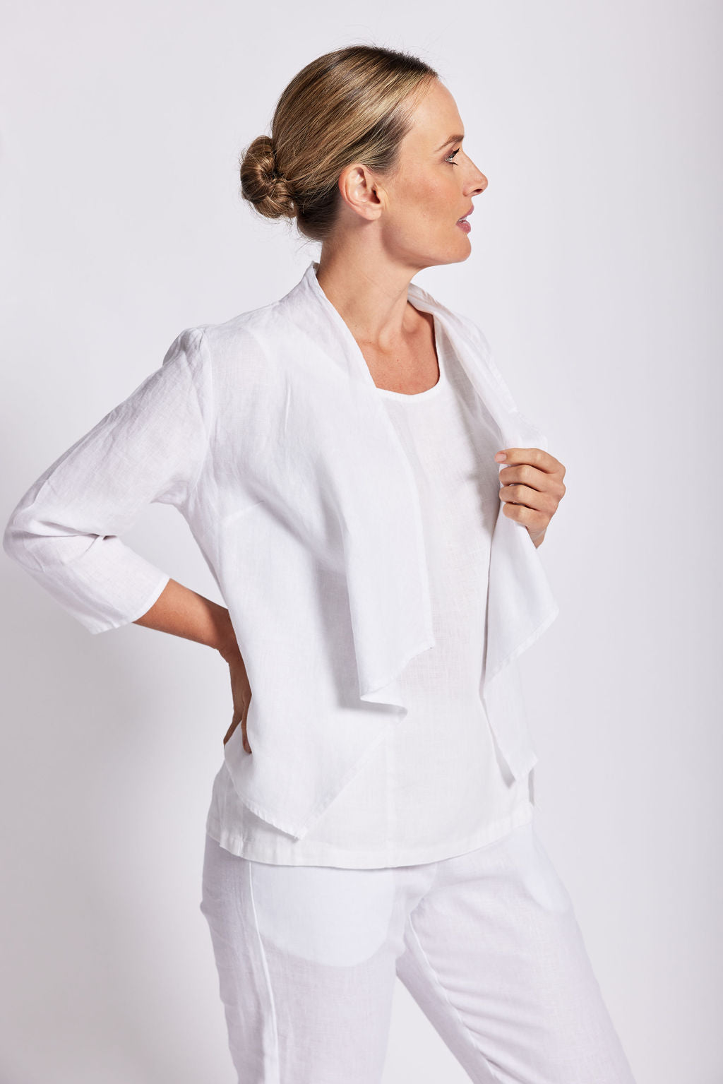 Woman modelling a white drape jacket by see saw in a studio. 