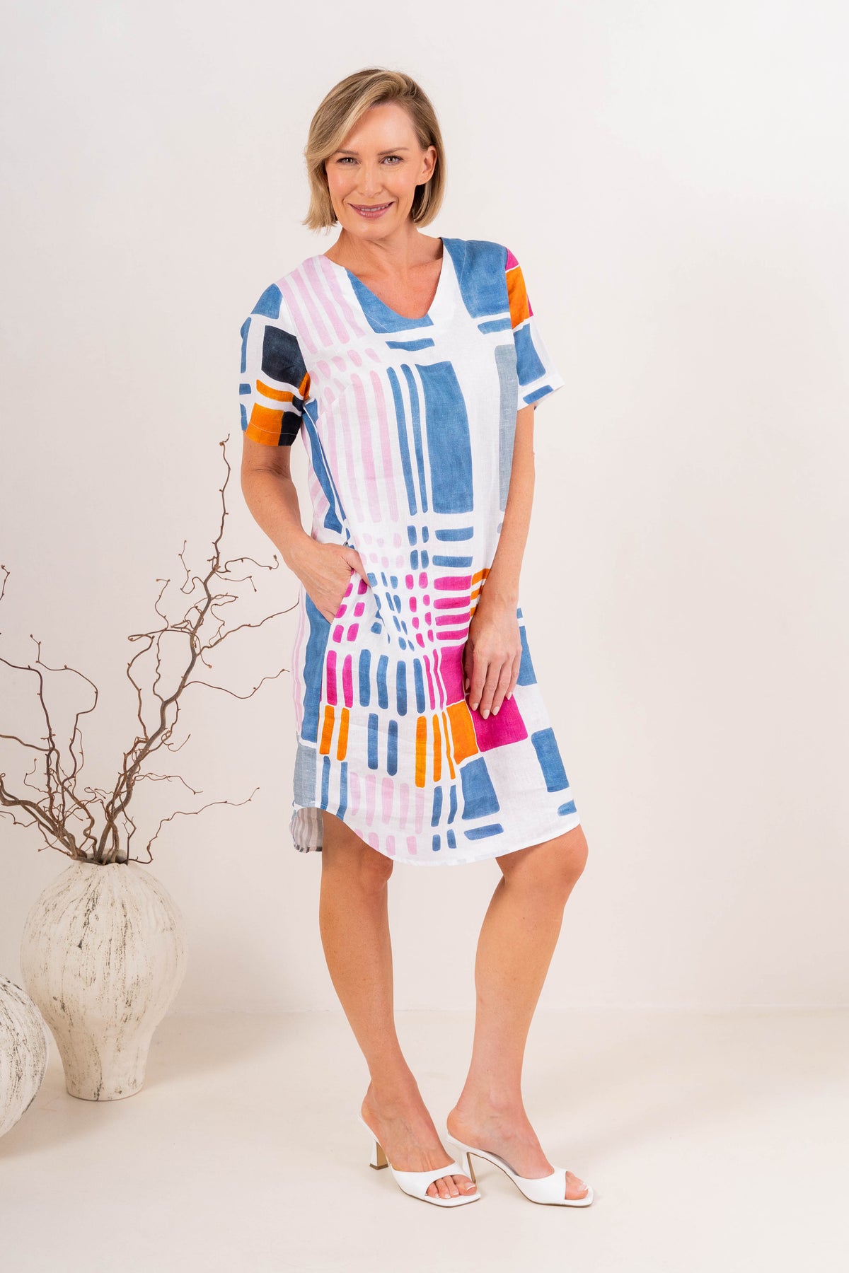 Woman modelling gallery print see linen dress in a neutral studio setting.