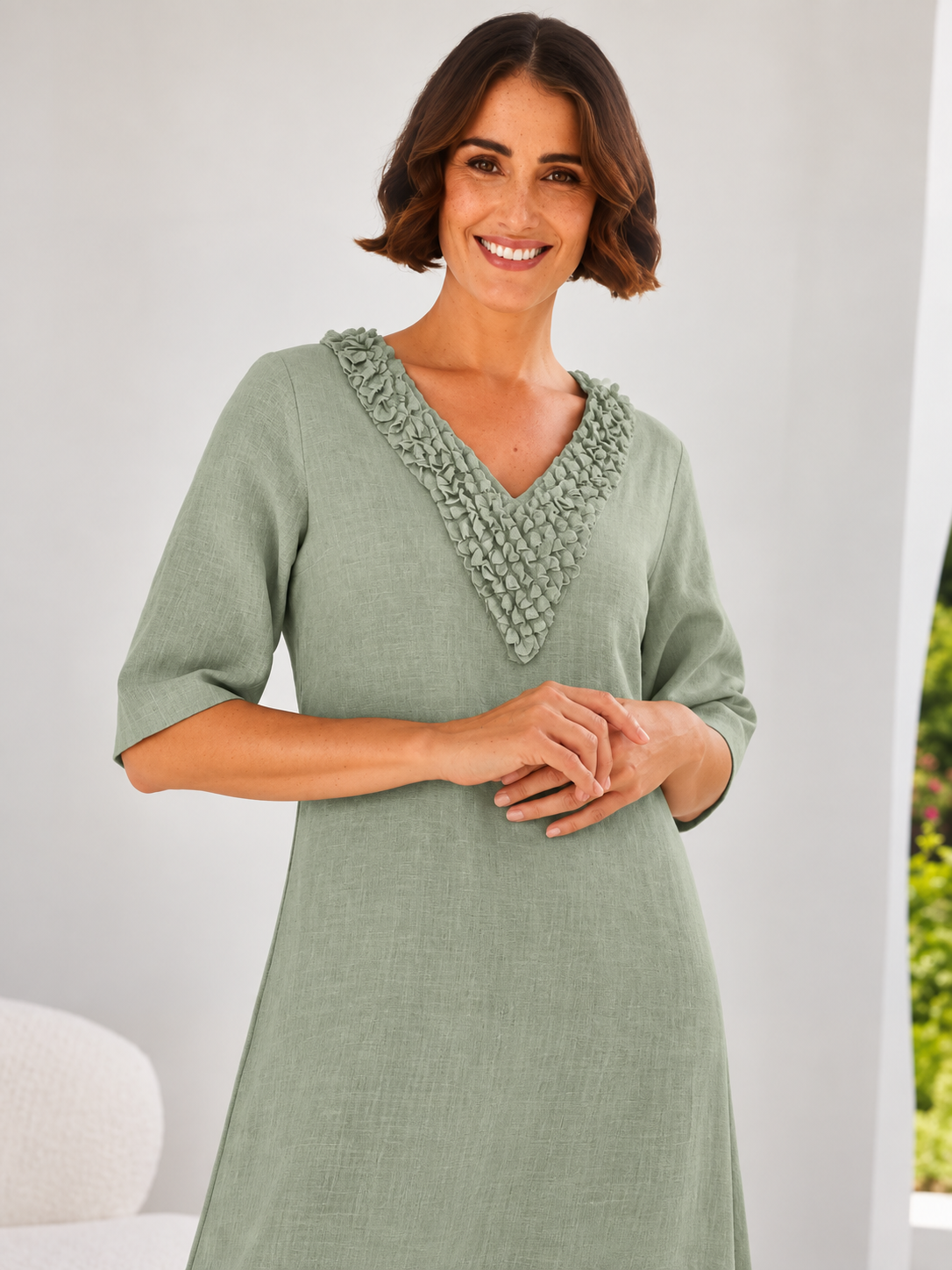 woman wearing linen see saw dress in white in architectural outdoor space.