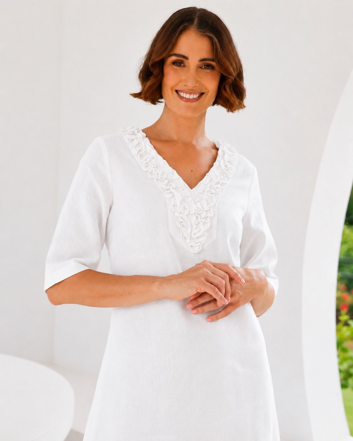 woman wearing linen see saw dress in white in architectural outdoor space.