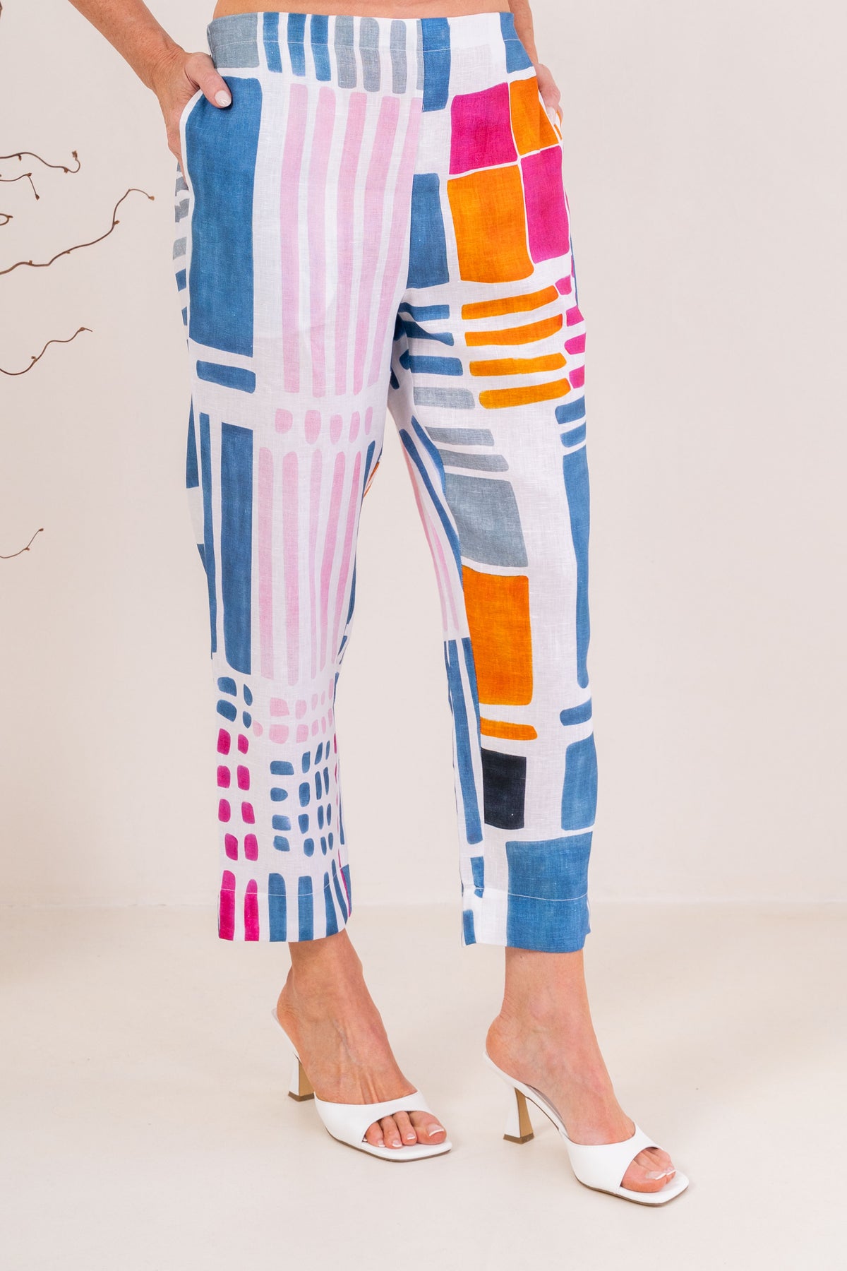 Woman modelling 100% linen See Saw pant in gallery print and in a 7/8 length. Modelling against a neutral studio background. 
