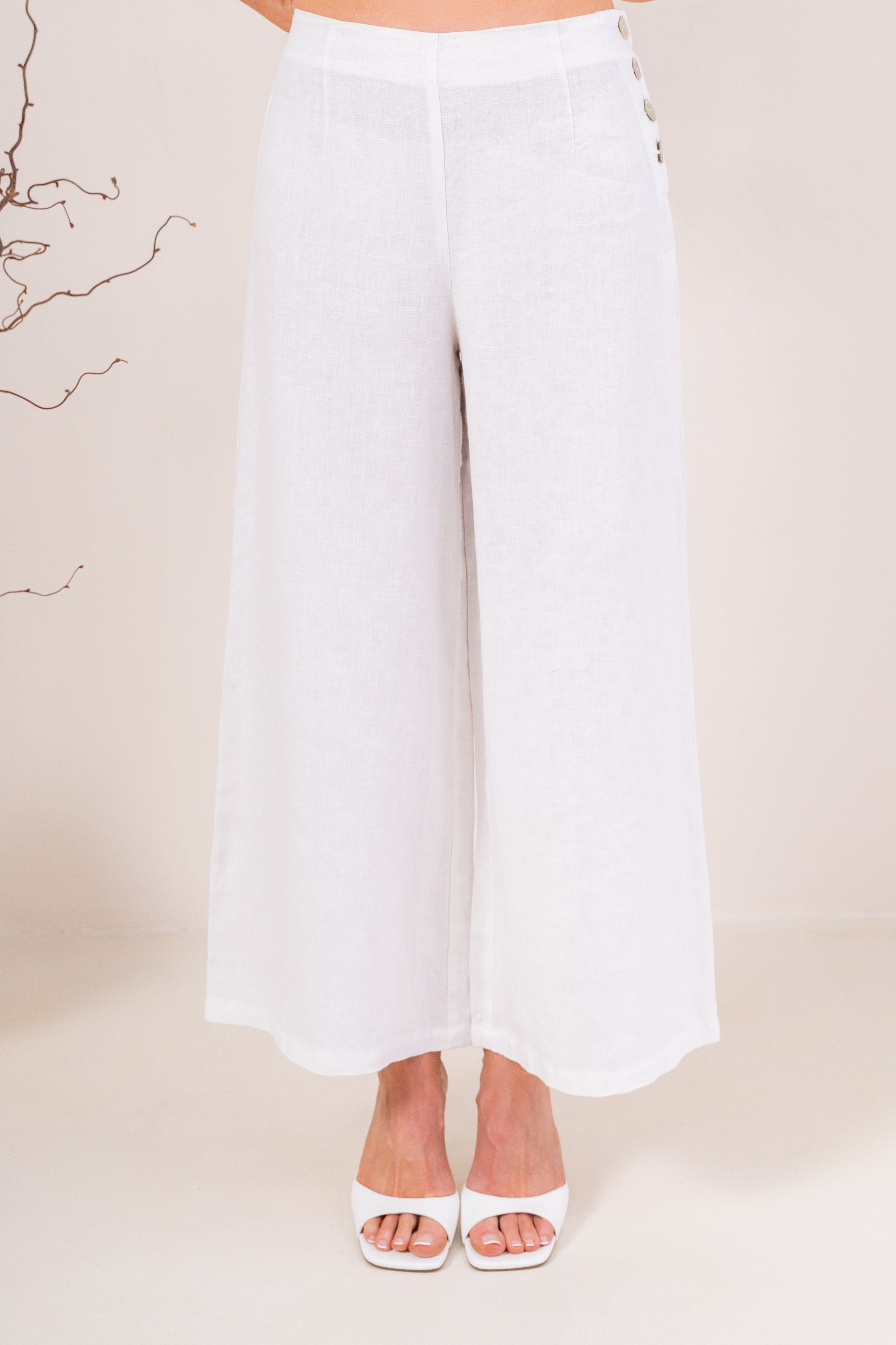 White wide-leg See Saw Palazzo linen pants shown on a model wearing white heeled sandals against a light beige background.