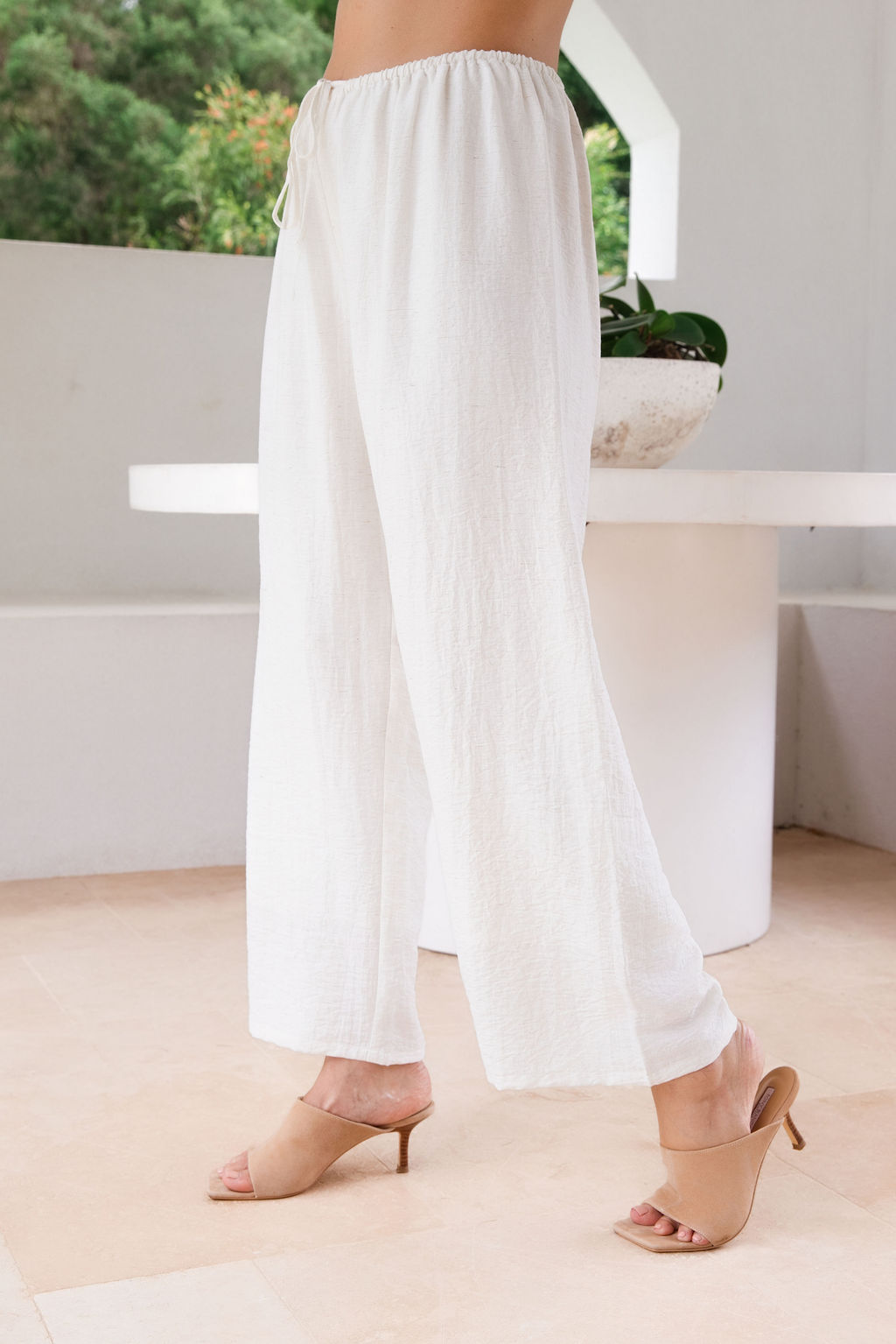 Model wearing See Saw Matching tank and pant in navy in linen and rayon blend. standing in an outdoor architecturally designed patio. 