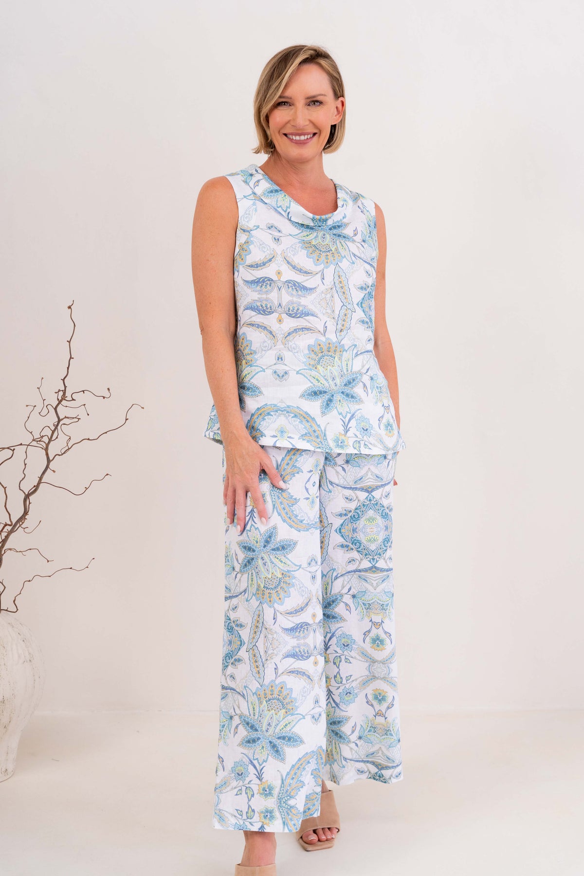 Woman modelling cowl neck linen dress in botanica print by see saw clothing. model is standing against a neutral 