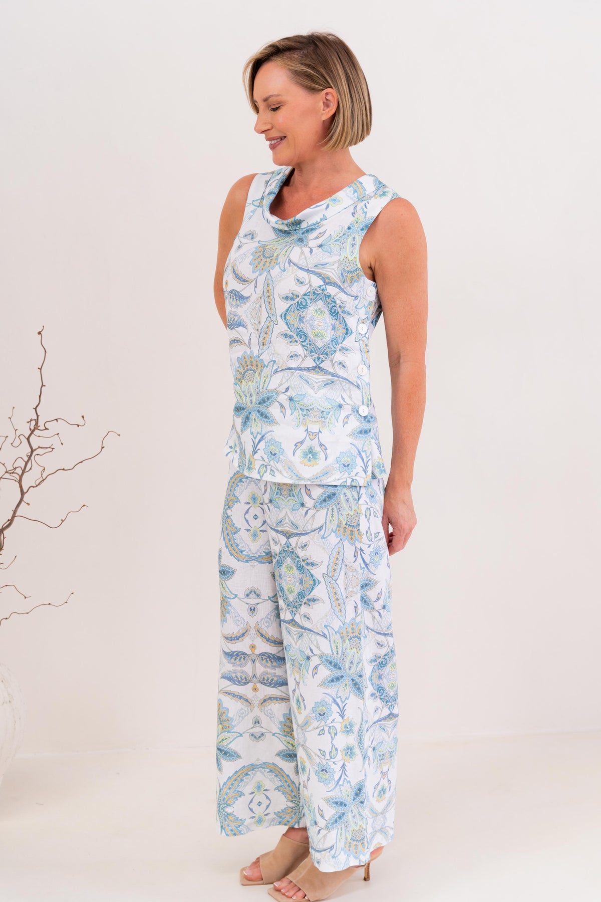 Woman modelling cowl neck linen dress in botanica print by see saw clothing. model is standing against a neutral 
