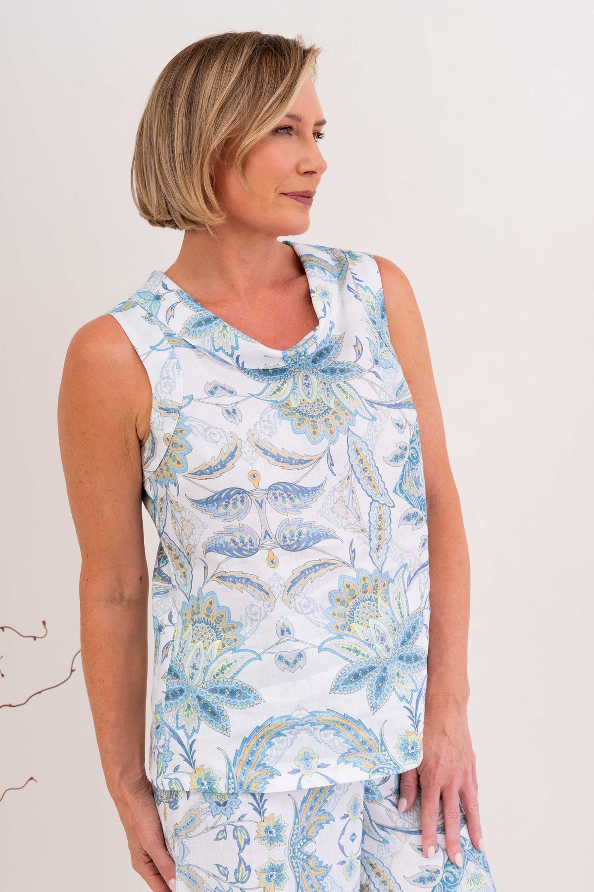 Woman modelling cowl neck linen dress in botanica print by see saw clothing. model is standing against a neutral 