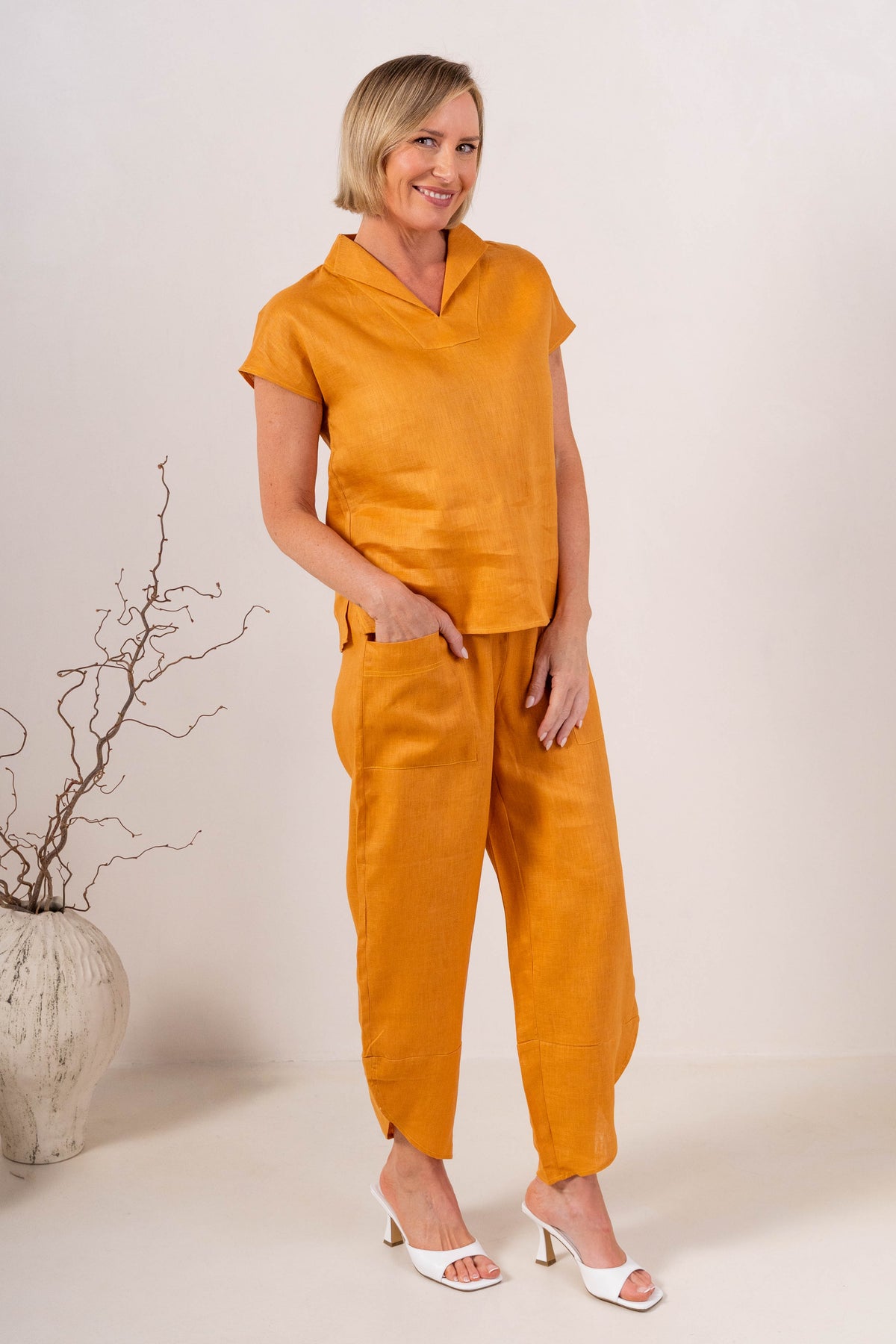 Women wearing 100% Linen See Saw top on stripe with a cap and  2 pocket pant in marigold against a neutral background