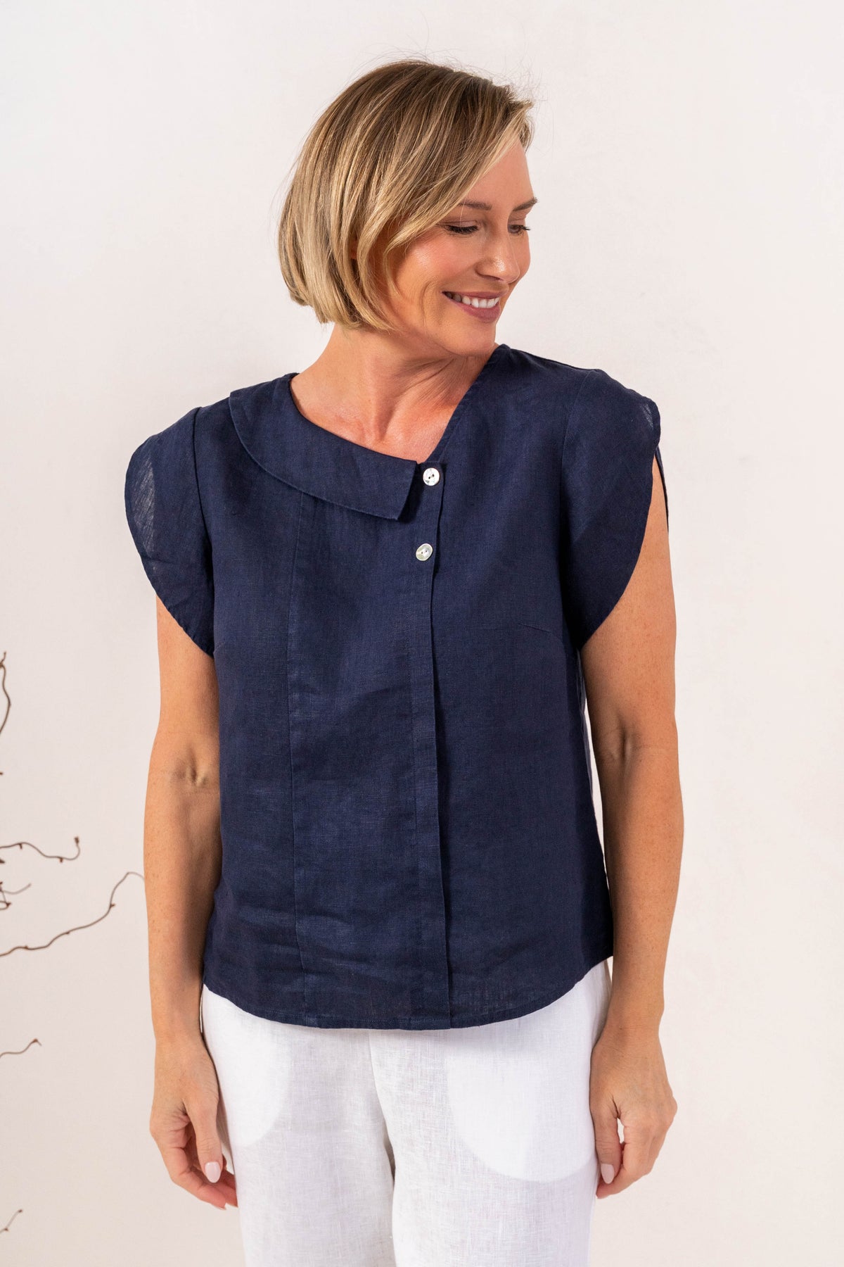 Model wearing see saw linen 2 button cowl neck top in navy.