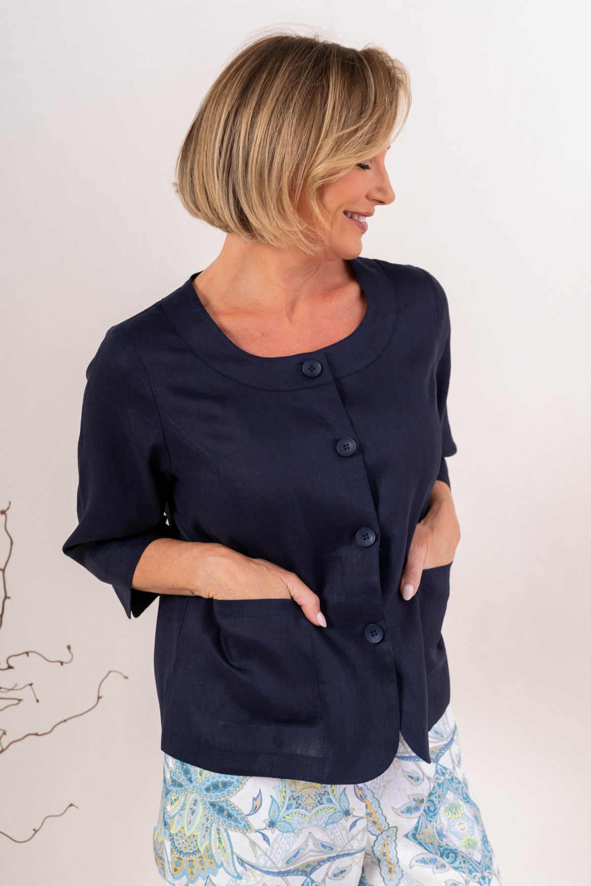 Woman modelling navy linen see saw utility jacket top against a plain background. 