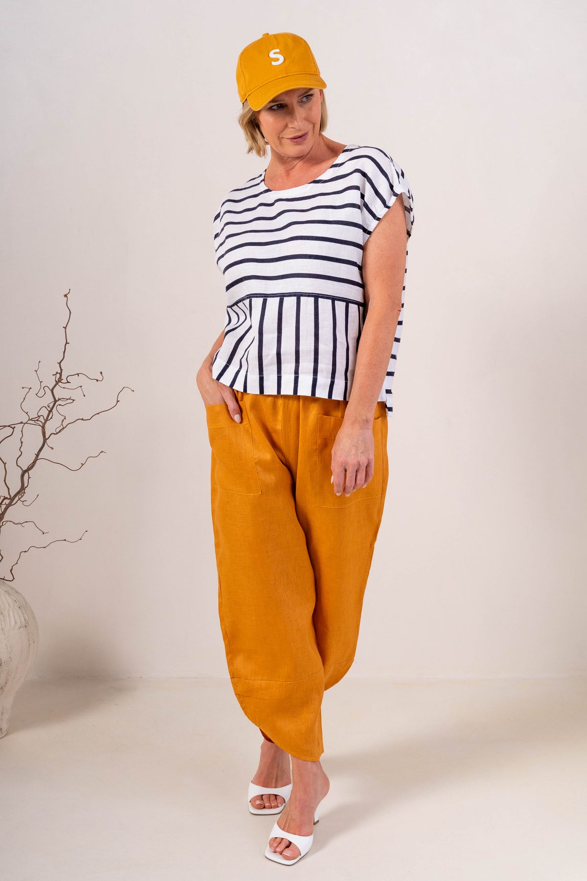 Women wearing 100% Linen See Saw top on stripe with a cap and  2 pocket pant in marigold against a neutral background