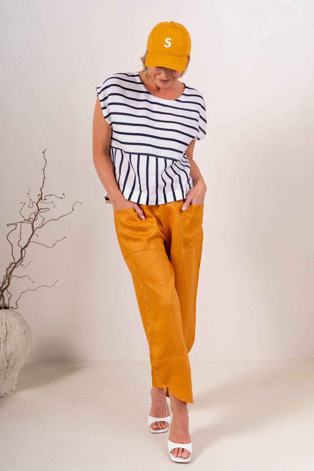 Women wearing 100% Linen See Saw top on stripe with a cap and  2 pocket pant in marigold against a neutral background