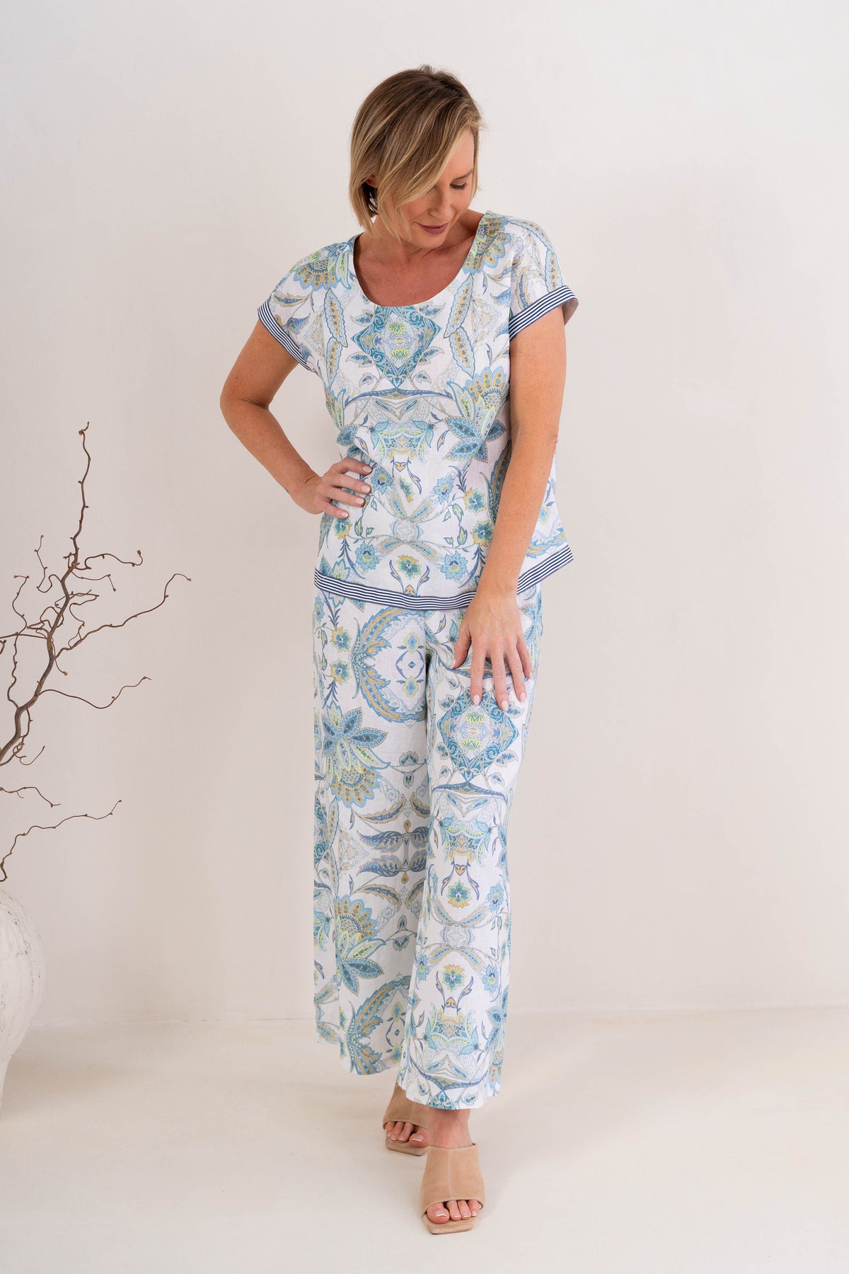 Woman wearing pure linen botanica print cap sleeve top against a neutral background. 