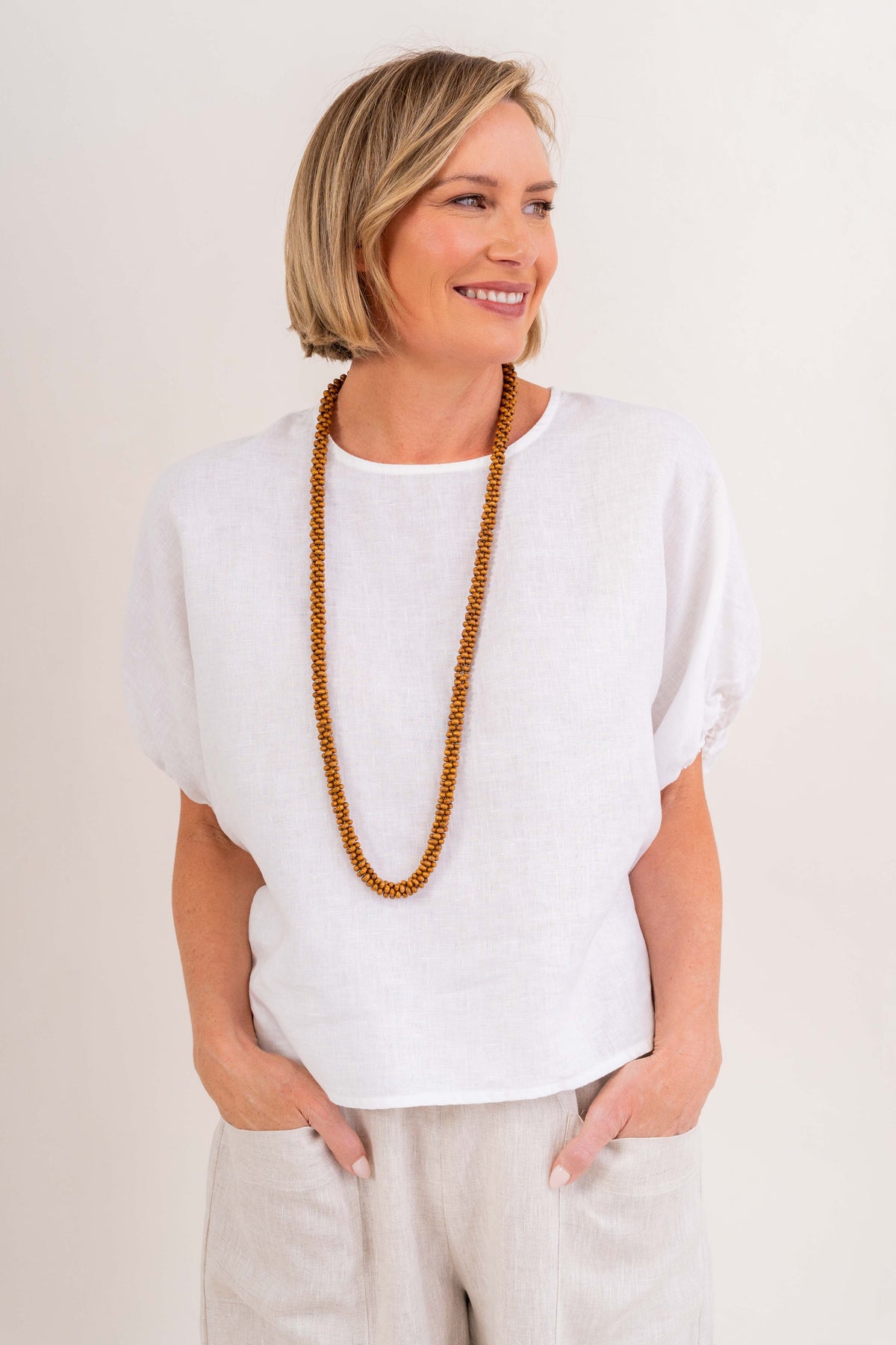 Model wearing See Saw 100% Linen elastic sleeve top with necklace.
