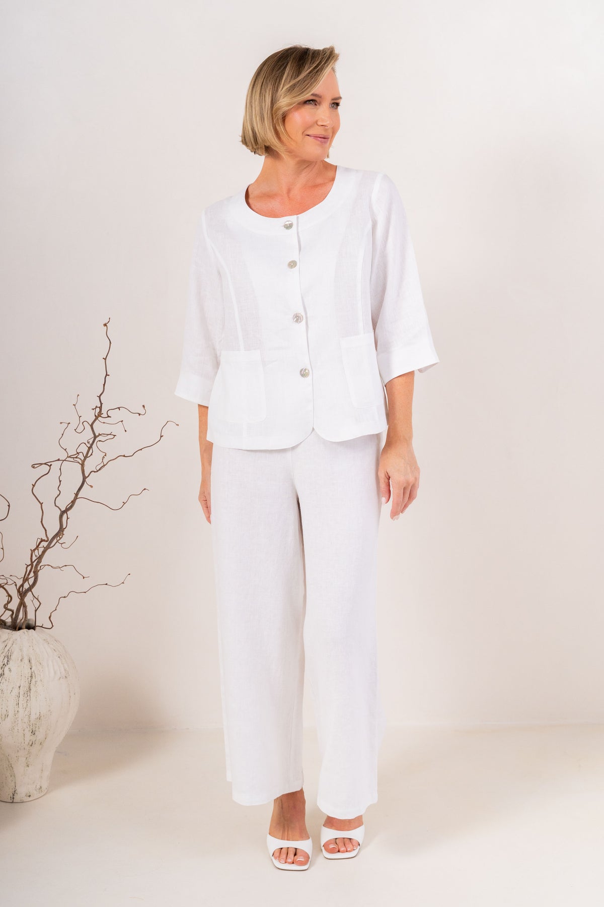 White wide-leg See Saw Palazzo linen pants shown on a model wearing white heeled sandals against a light beige background.