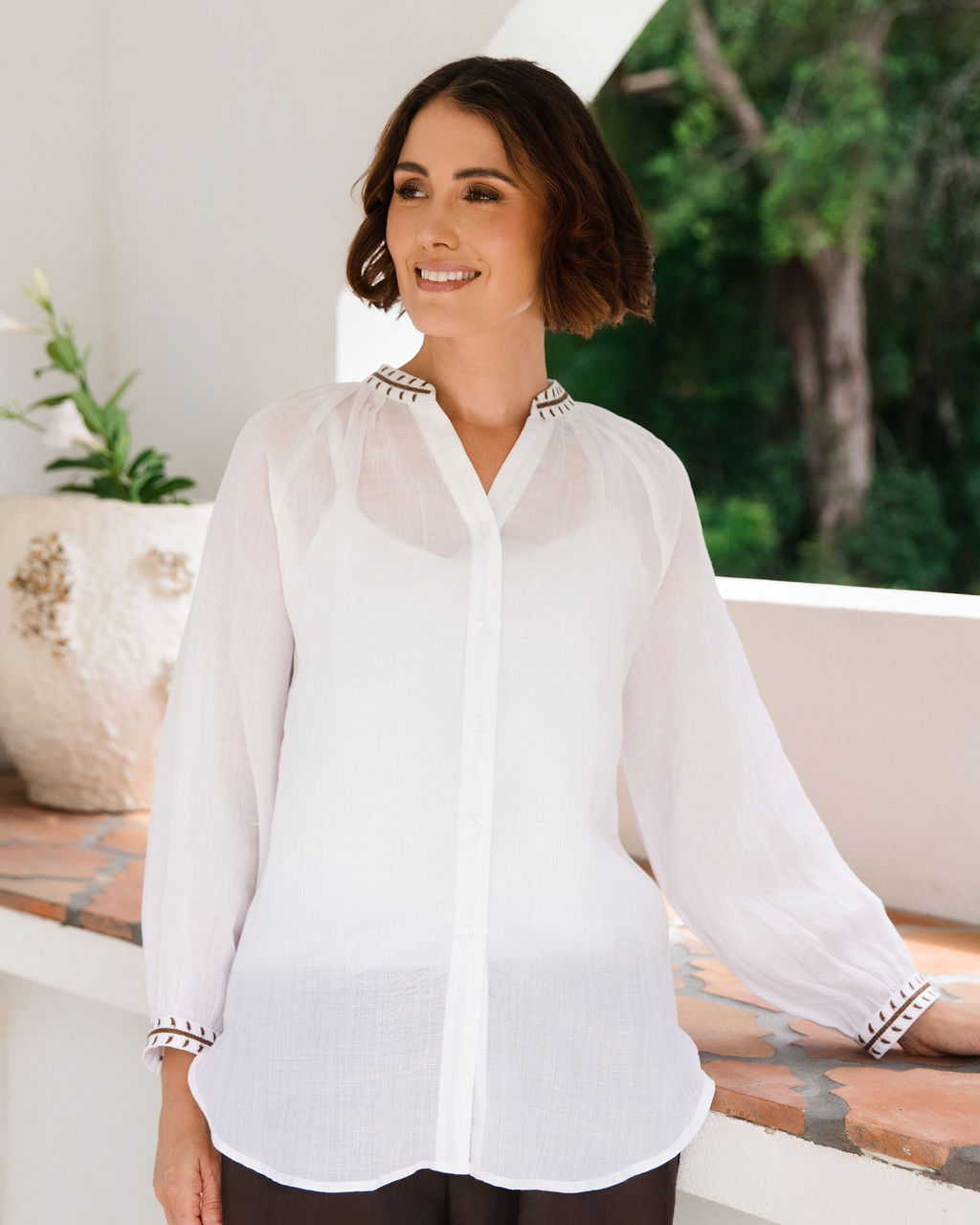 Women modelling white rami top with embroidery by See Saw in an outdoor architectural setting.