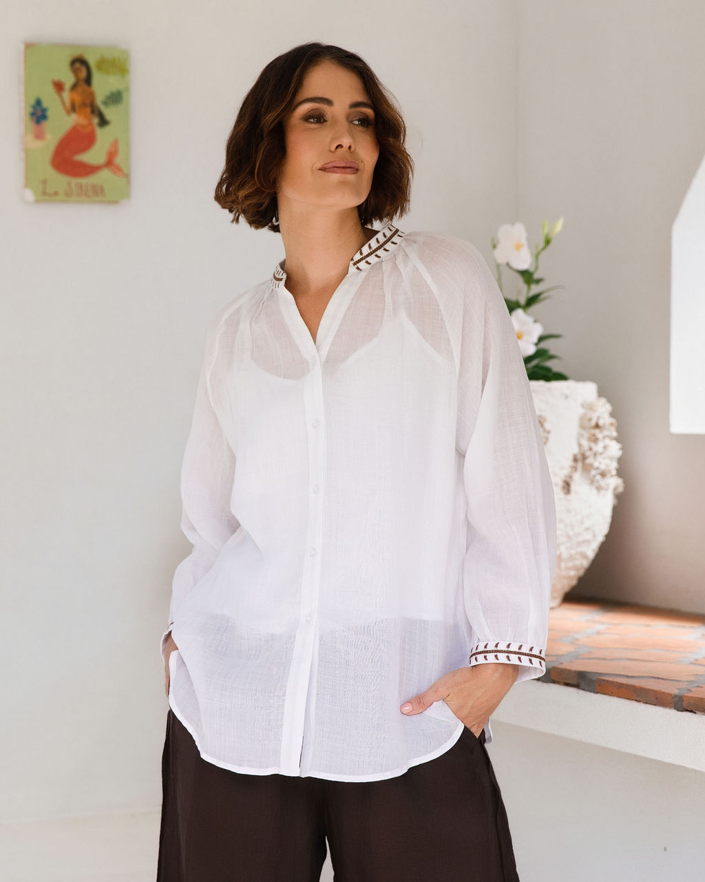 Women modelling white rami top with embroidery by See Saw in an outdoor architectural setting.