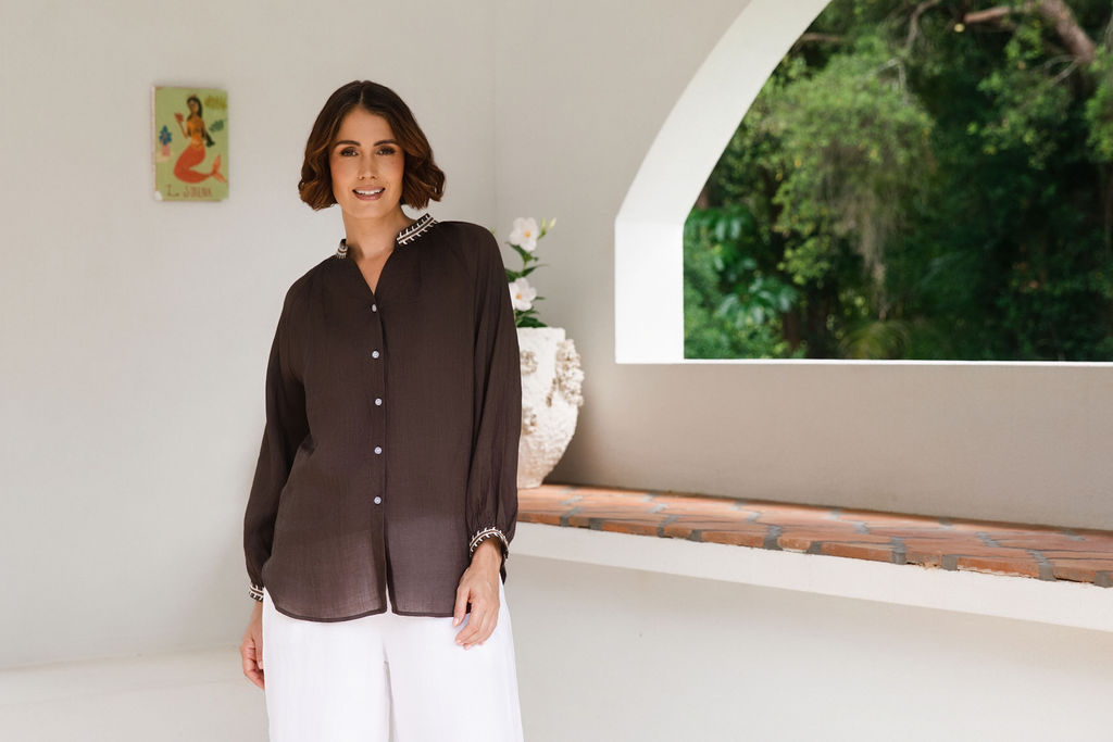 Women modelling espresso rami top with embroidery by See Saw in an outdoor architectural setting.