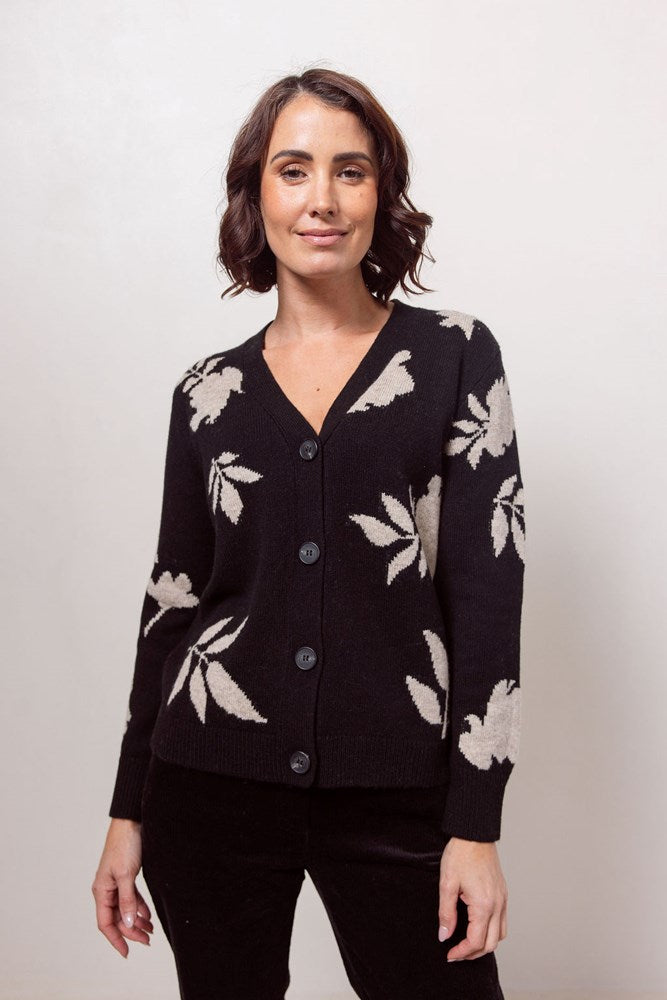 Woman wearing a black See Saw cardigan with white floral patterns against a plain background
