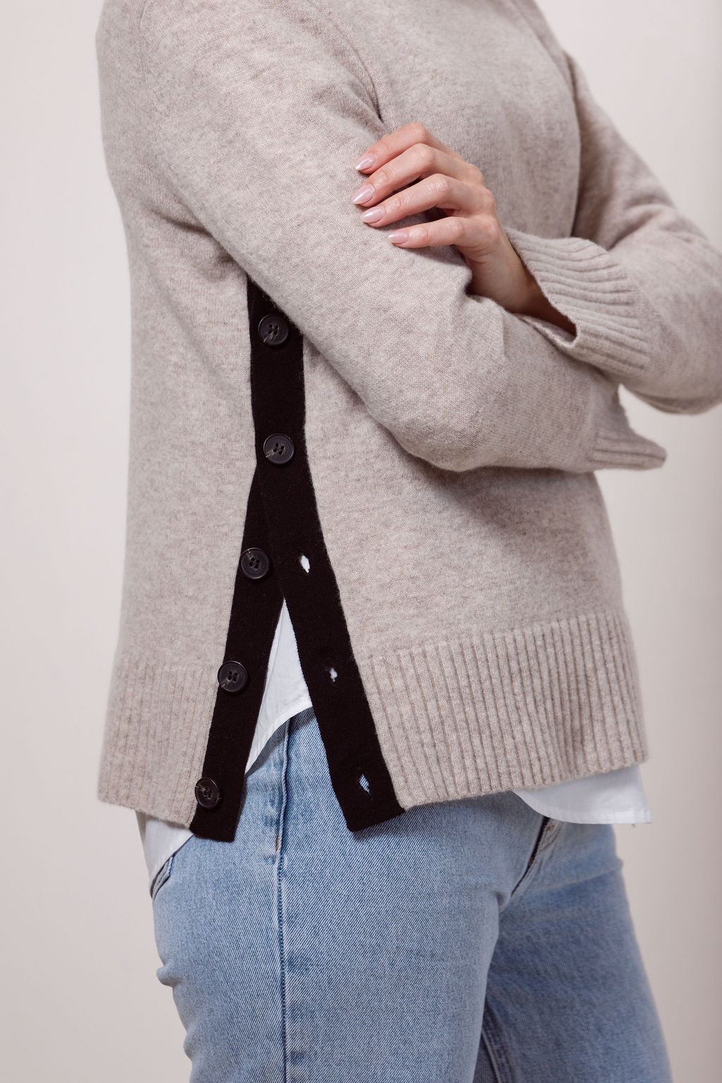 Woman wearing a Merino Wool See Saw sweater in wheat with Black accents on a plain background