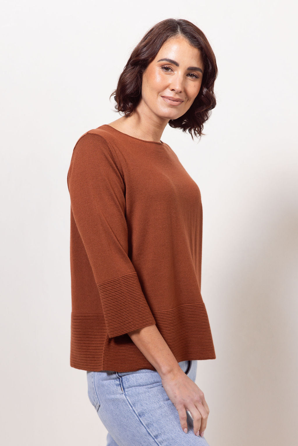 Woman wearing a copper See Saw Merino Wool  sweater and patterned scarf against a white background