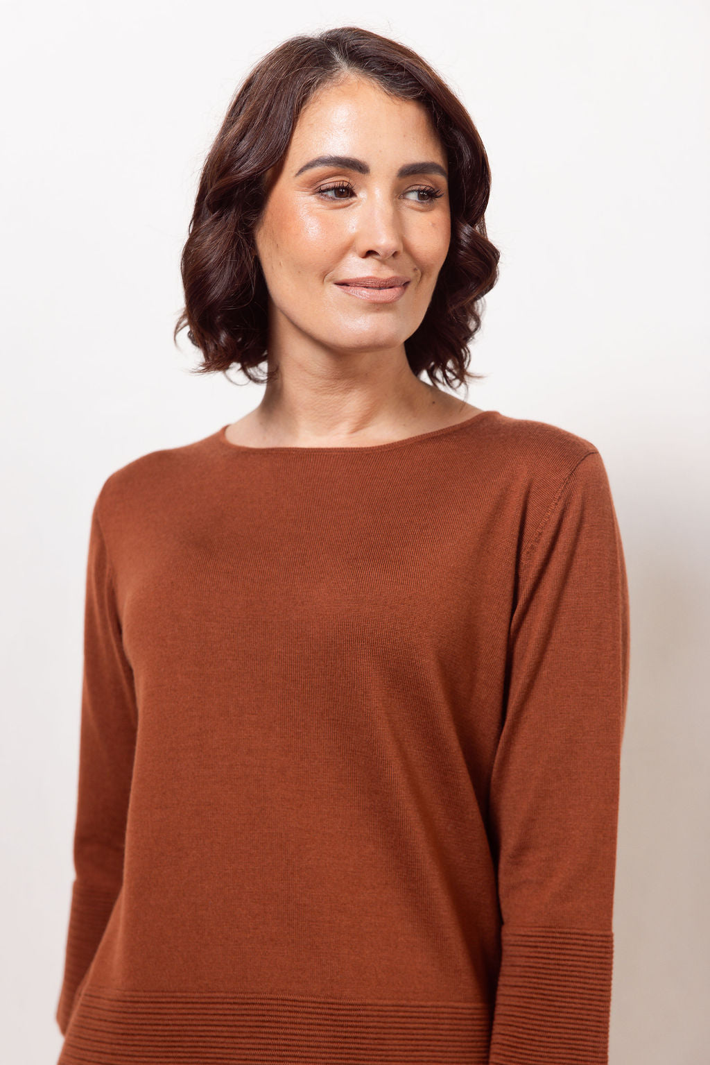 Woman wearing a copper See Saw Merino Wool  sweater and patterned scarf against a white background