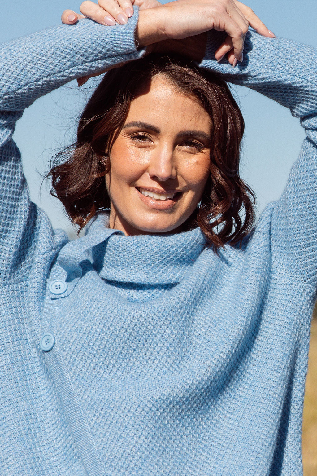Woman wearing a powder blue Cowl Neck Moss Stitch See Saw sweater with an outdoor background